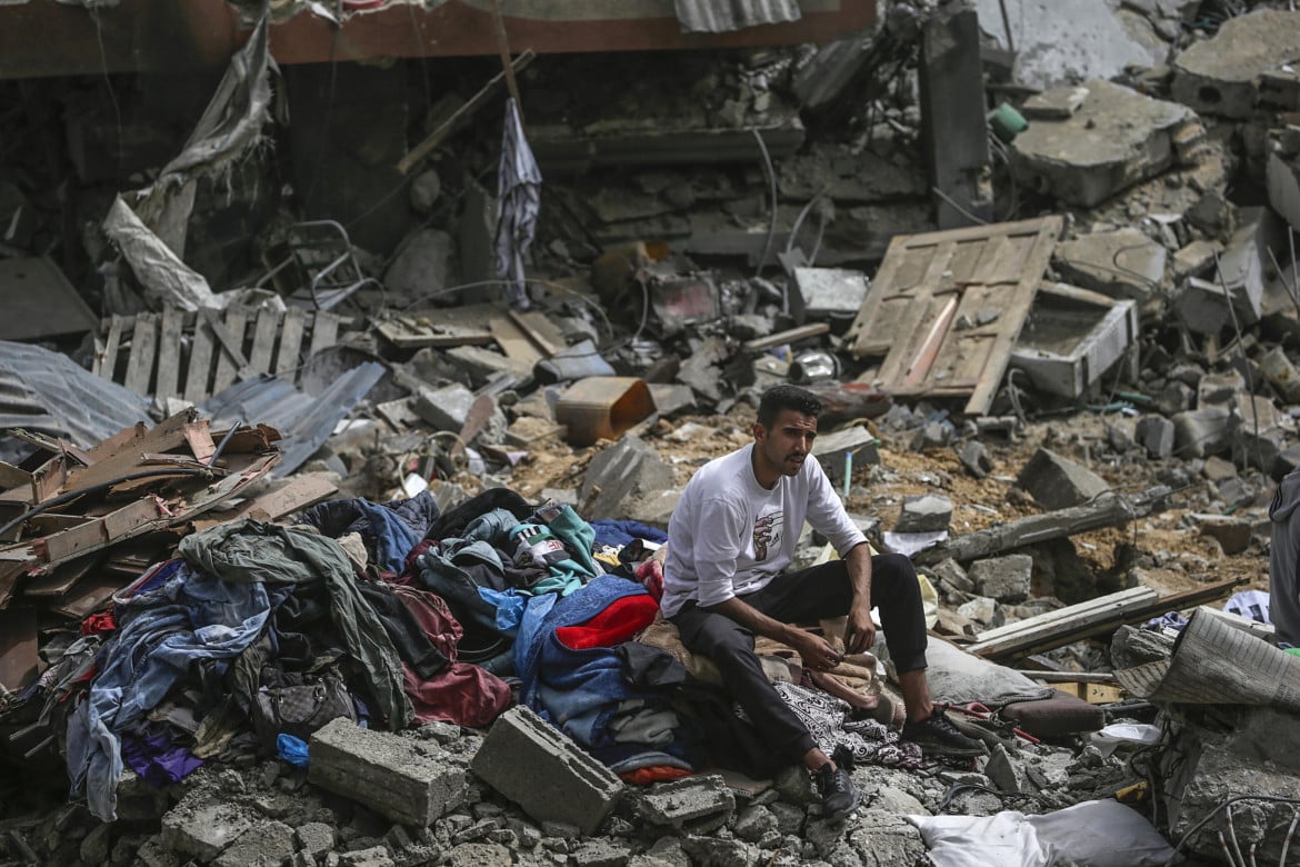 Un ragazzo siede su delle rovine a Gaza, foto Ansa
