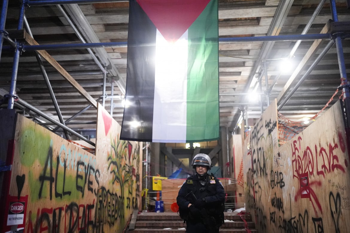 010 Un agente di polizia in piedi sotto una bandiera palestinese dopo un raid in un accampamento nel campus dell'UCLA (Jae C. Hong, Ap)